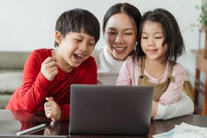 Mother and two children smiling together in front of a laptop